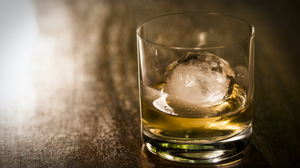 Faceted glass of whiskey with ice